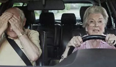 Two women in a car with one holding the steering wheel.