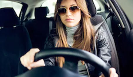 A woman in sunglasses driving a car.